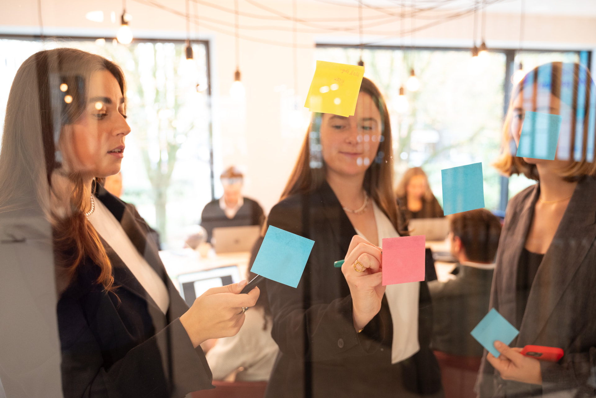 ESGlogic-team die samenwerkt met post-its op een glazen wand